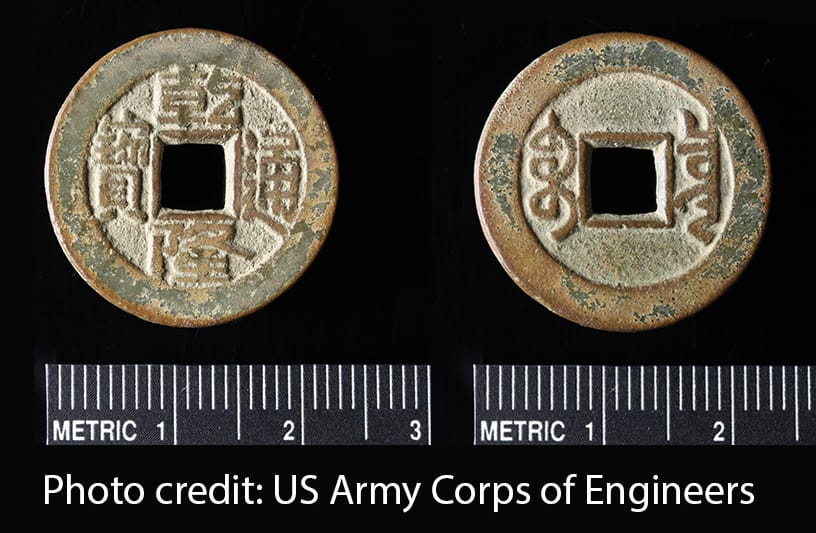Two sides of the same coin. A round metal coin with a square hole in the center and Chinese characters. The coin is shown with a scale and is about 2 cm in diameter.